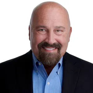 Professional business headshot of man with bald head and full brown goatee and mustache with warm smile wearing navy blue suit jacket over light blue striped dress shirt photographed against white studio background by Richard Waine Photography Lancaster Pennsylvania