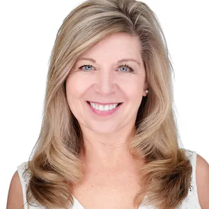 Professional business headshot of woman with shoulder-length blonde highlighted hair styled in soft layered waves and warm engaging smile wearing white sleeveless shell top photographed against seamless white studio backdrop with high-key professional lighting by Richard Waine Photography headshot photographer serving Lancaster Harrisburg York Philadelphia Pennsylvania
