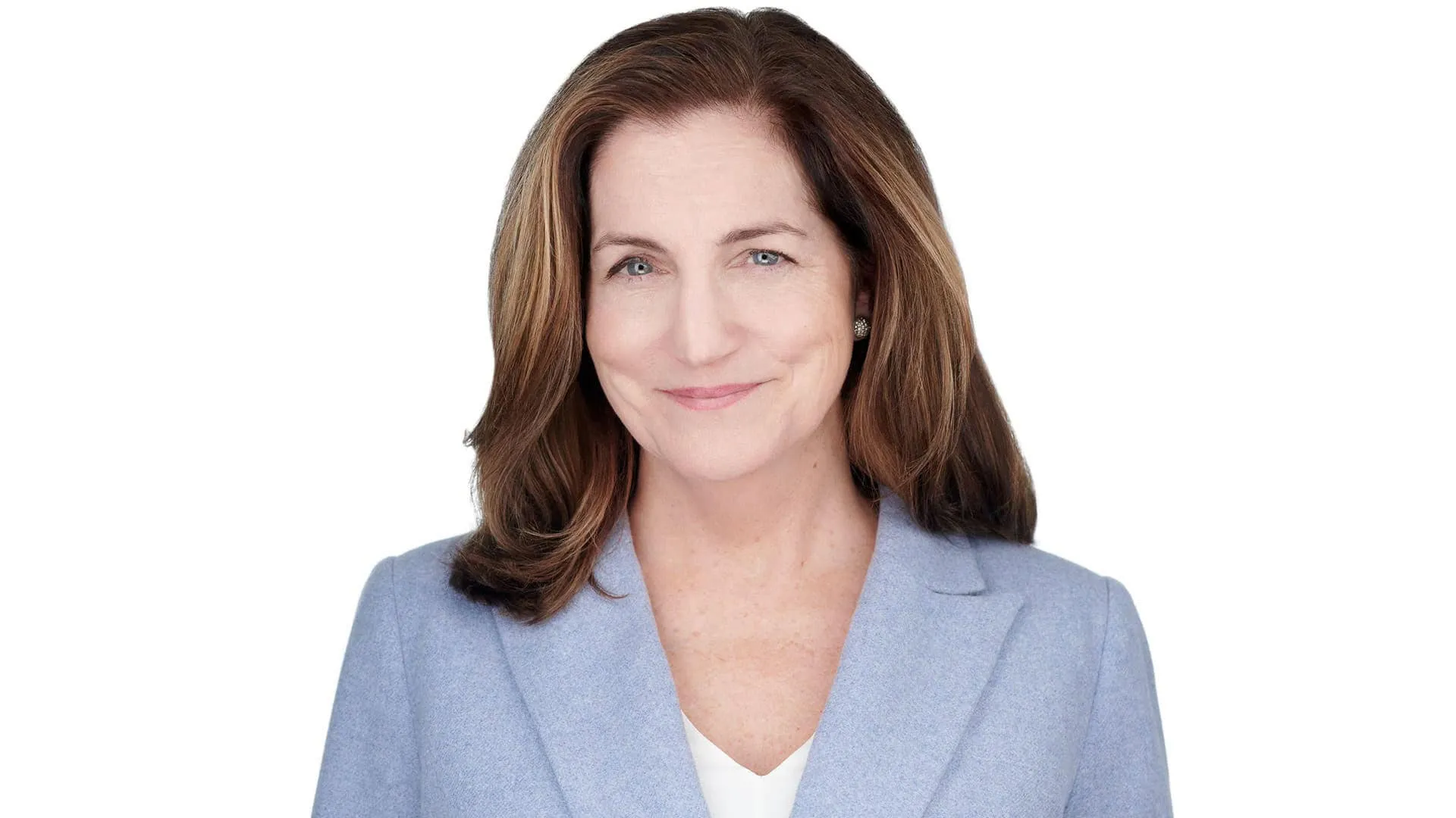 Professional headshot of female with long brown hair with blonde highlights, small silver stud earrings, wearing light blue blazer over white v-neck top, photographed on seamless white background by Lancaster Pennsylvania headshot photographer Richard Waine