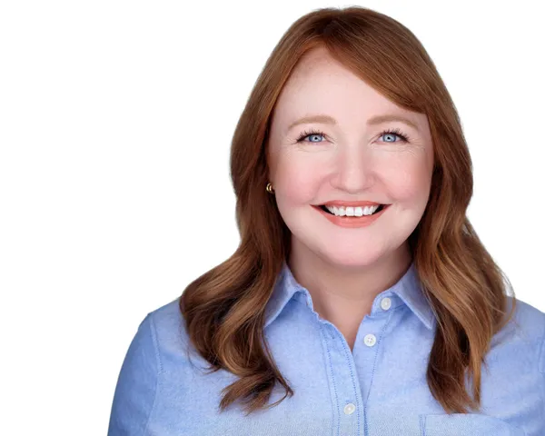 Professional acting headshot of woman with red hair in light blue shirt, smiling warmly against white studio background, headshot made by Richard Waine in Lancaster Pennsylvania