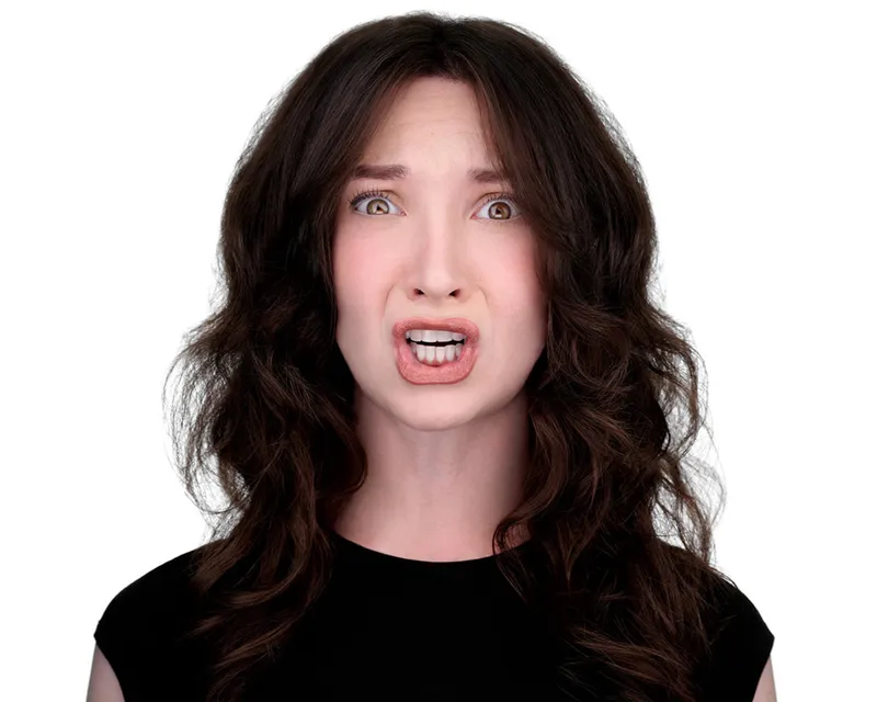 Expressive actor headshot of woman with long voluminous dark brown wavy hair with caramel highlights showing animated surprised expression with wide eyes and open mouth wearing black cap sleeve top photographed against seamless white studio backdrop with professional lighting by Richard Waine Photography