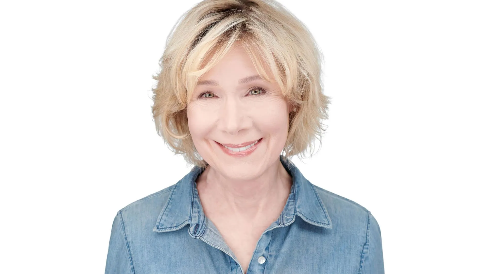 Professional headshot of female with short blonde wavy layered bob hairstyle, bright white smile showing teeth, wearing light blue denim collared shirt, photographed on seamless white background in Lancaster, Pennsylvania by headshot photographer Richard Waine