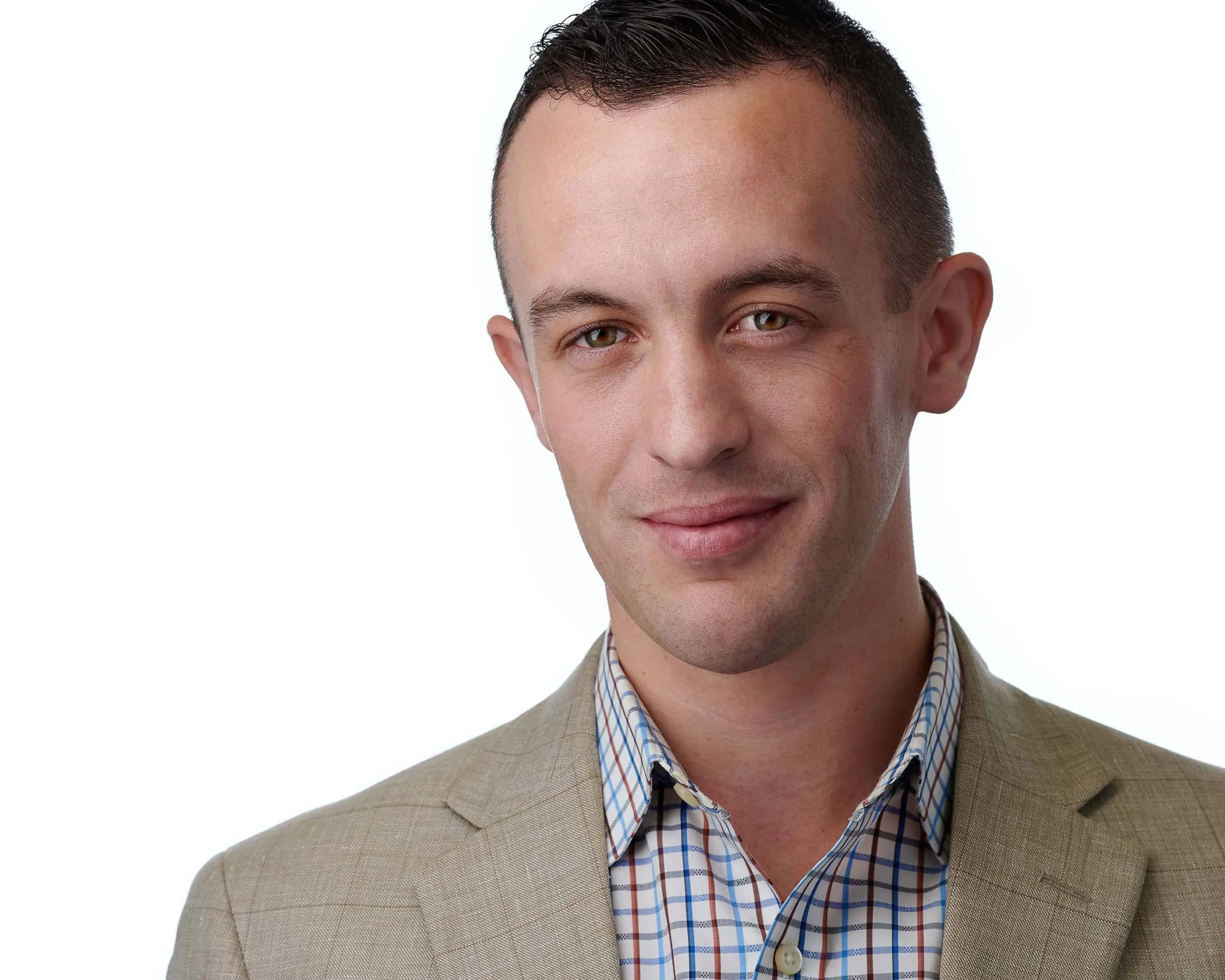 Male professional headshot with short dark brown hair, wearing tan beige sport coat over blue white and orange plaid button-down shirt, photographed on seamless white background by Lancaster Pennsylvania photographer Richard Waine