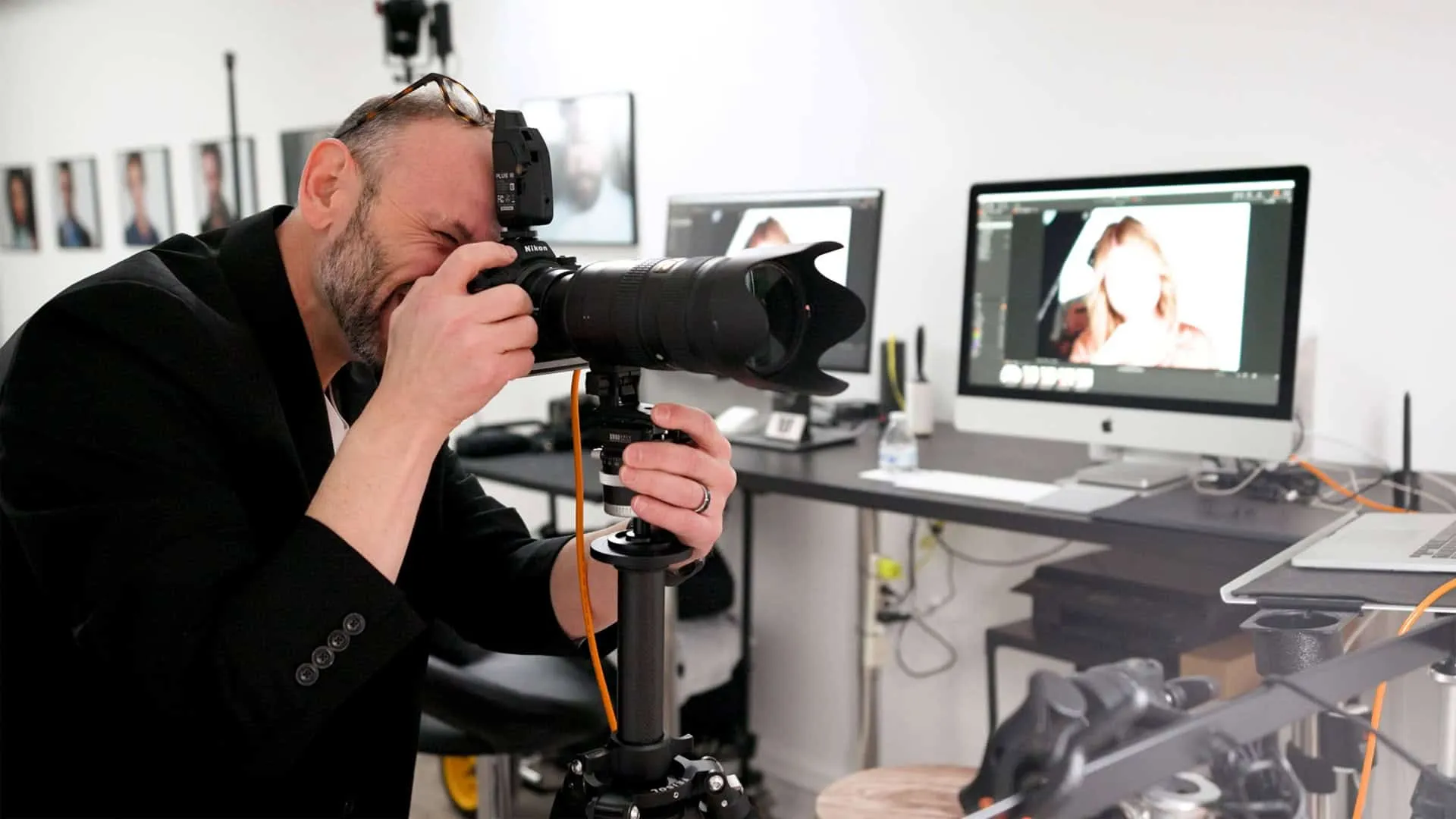 Professional headshot photographer Richard Waine photographing a client in Lancaster PA studio with dual monitor setup displaying headshots for Linkedin profiles