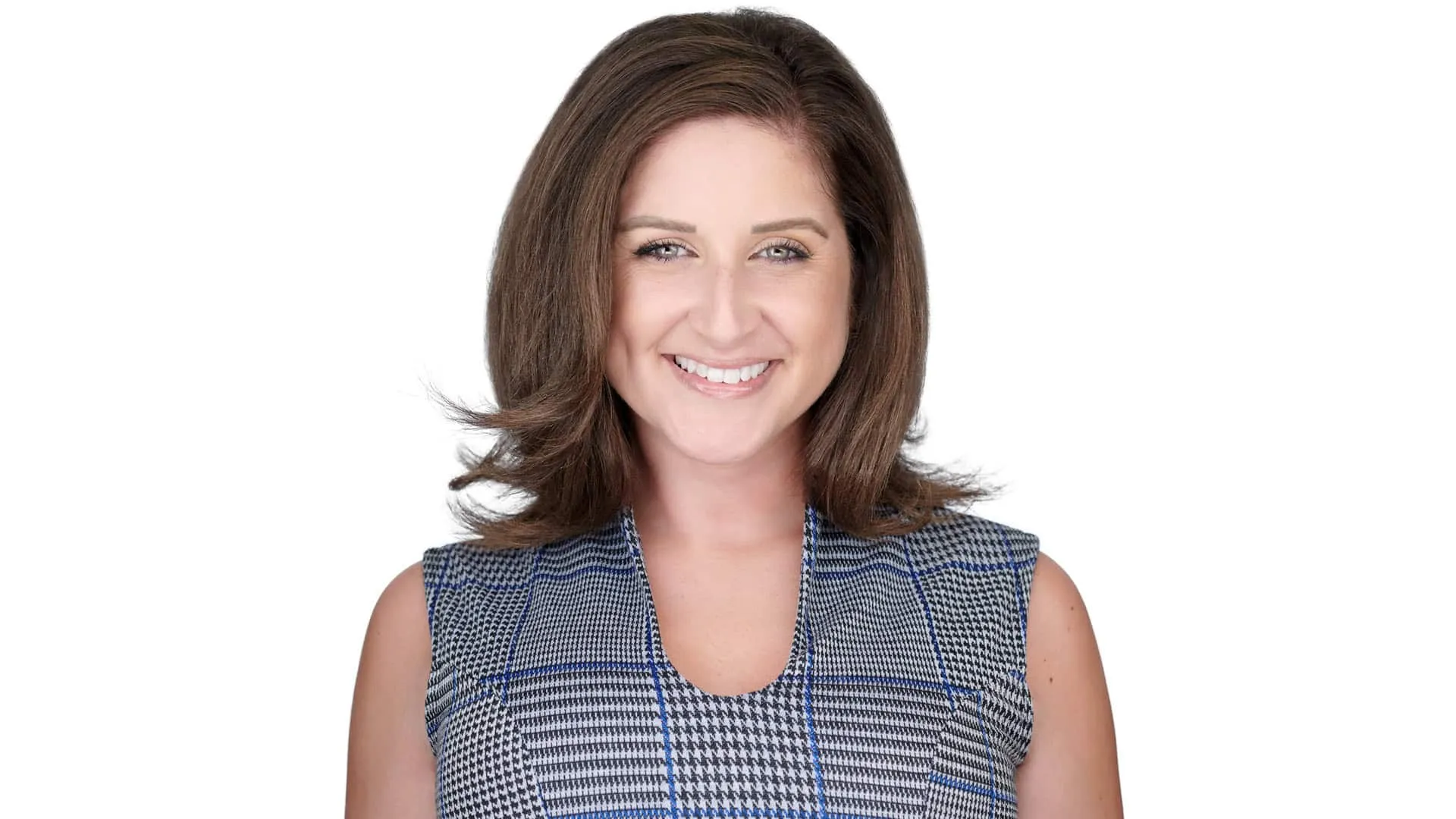 Woman with brown hair in blue houndstooth dress against white studio background with bright smile