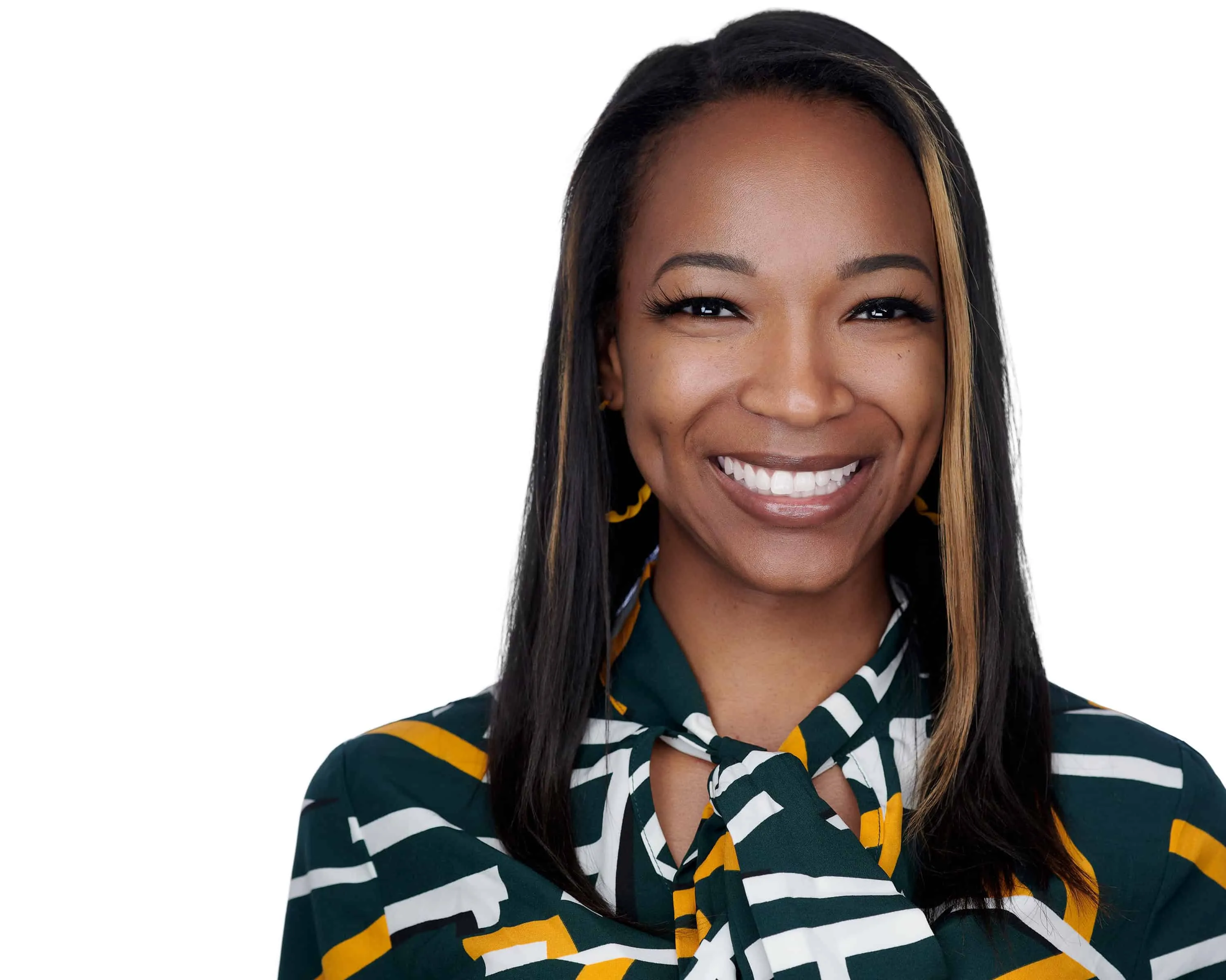 Professional corporate headshot of African American woman with medium brown skin tone and long straight dark hair with blonde and caramel highlights framing face wearing dark forest green blouse with bold white and gold geometric striped pattern with gold mustard colored hoop earrings showing genuine warm expression photographed against seamless white background with professional high-key lighting by Richard Waine Photography Lancaster Pennsylvania