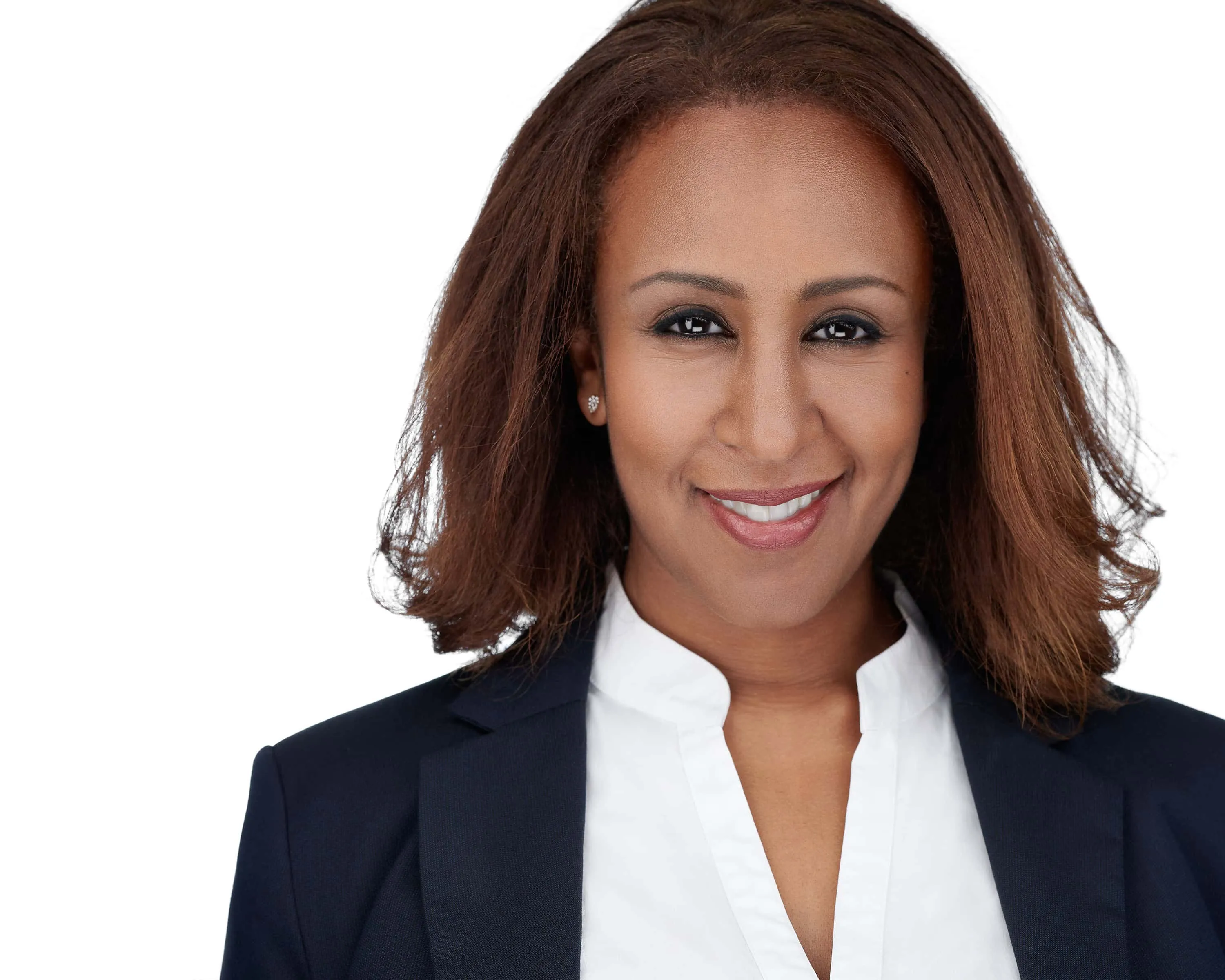 Professional headshot of Black female with shoulder-length brown wavy hair, gold stud earrings, wearing navy blue blazer over white collared shirt, warm smile showing teeth, photographed on seamless white background by Lancaster Pennsylvania headshot photographer Richard Waine